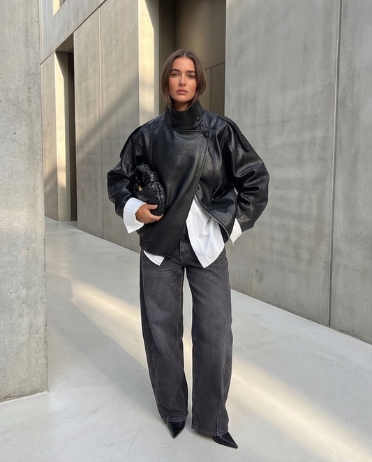 Veste en cuir noir pour femme style oversize tendance mode parisienne avec jean large et bottines élégantes.